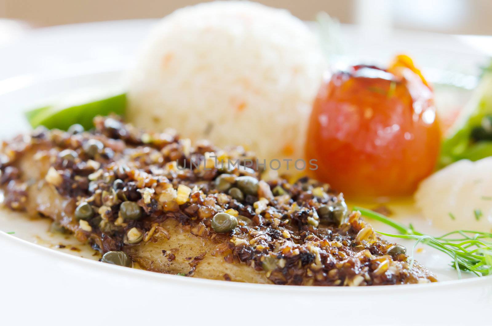 fish steak served with fried rice and vegetable on white dish