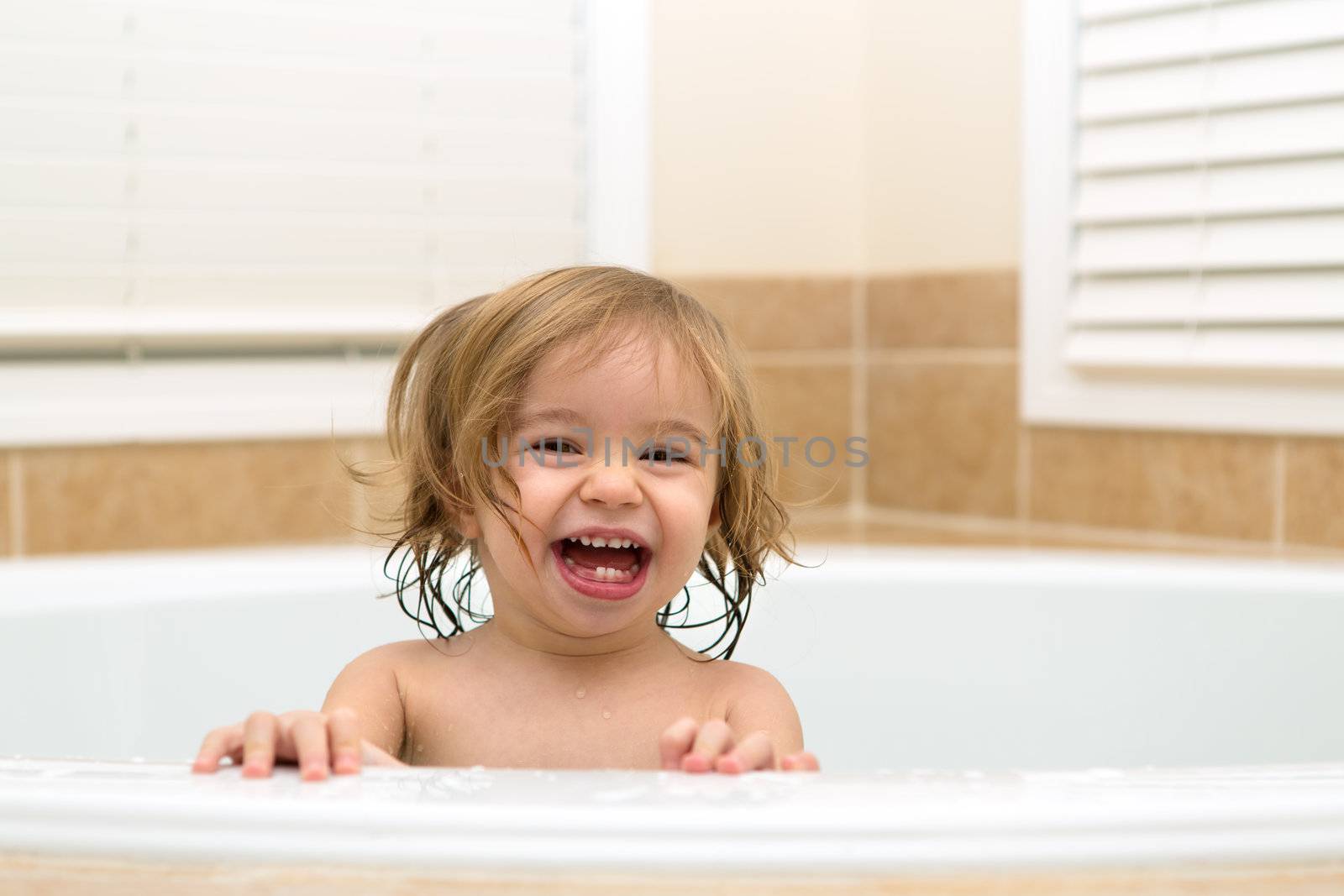 Toddler girl laughing happyly from bath tub,