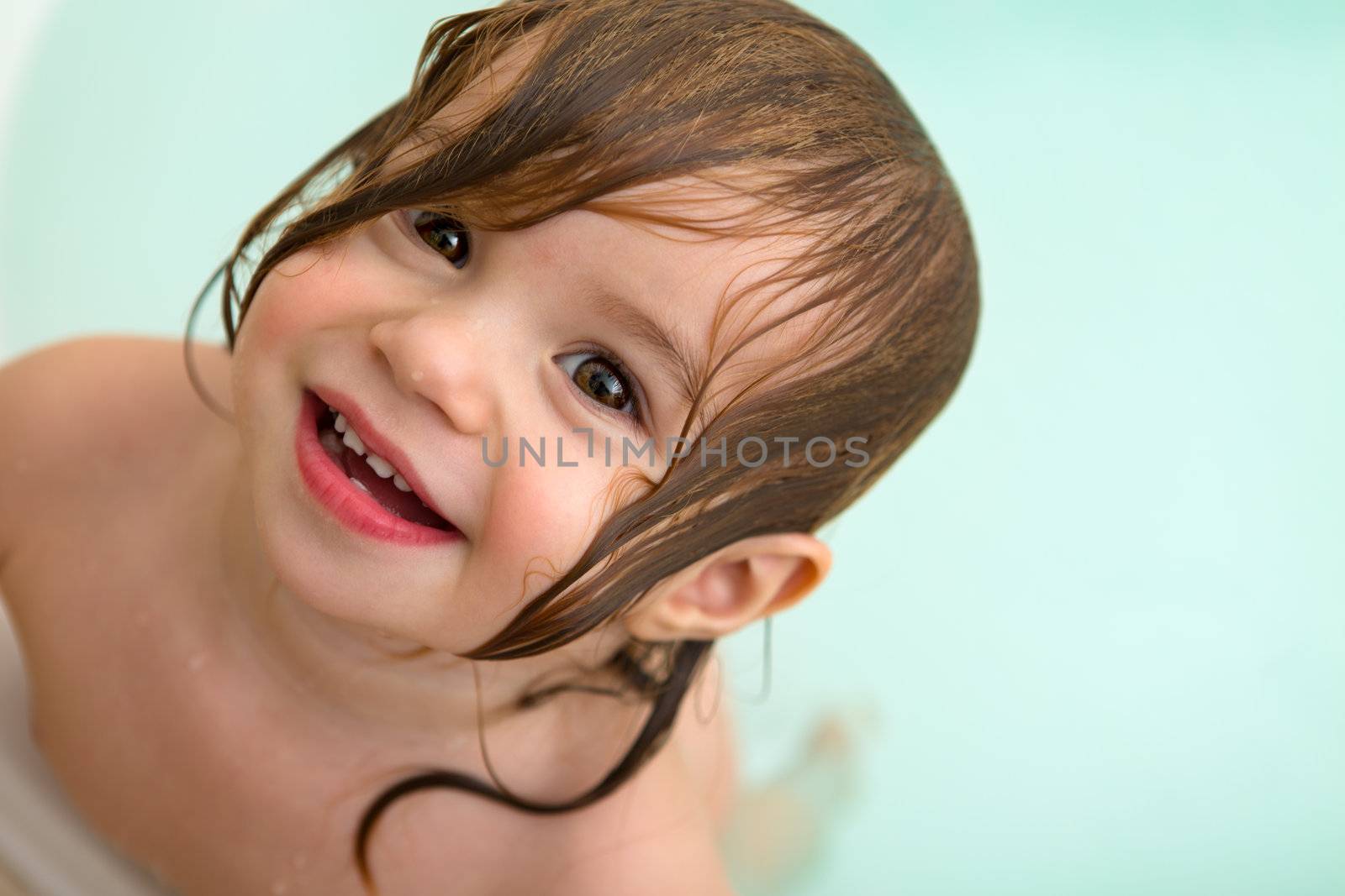 Cute Toddler girl giving happy trusty smile from the bath tub with her wet hair.