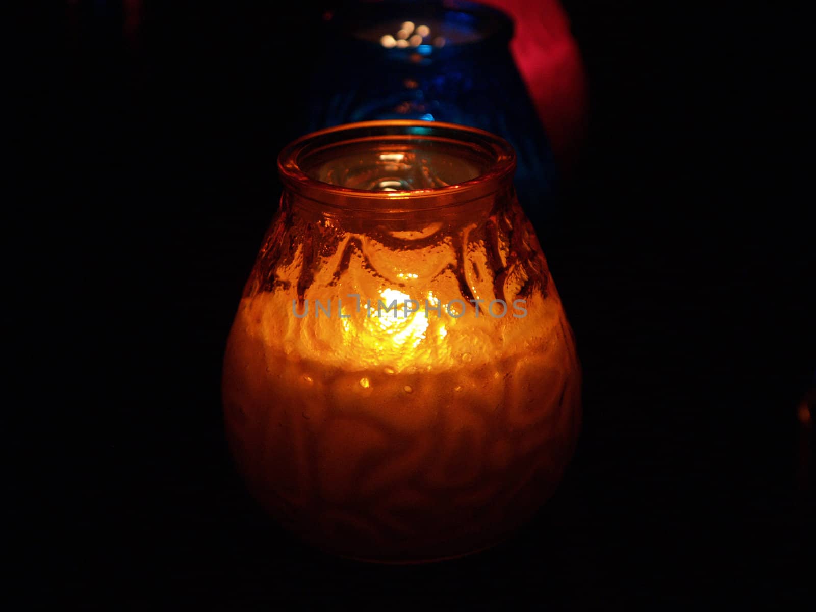 Candles in glass glow in the darkness to create romantic atmosphere