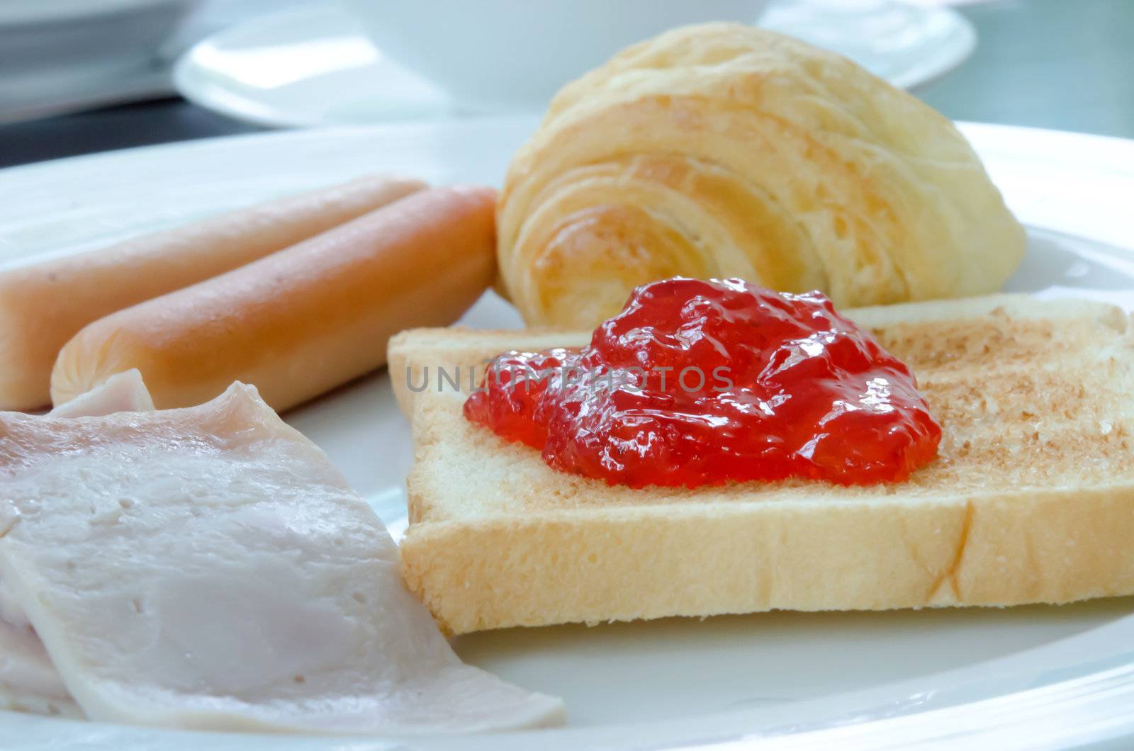 breakfast on white plate (bacon, bread , sausage , toast and jam) 
