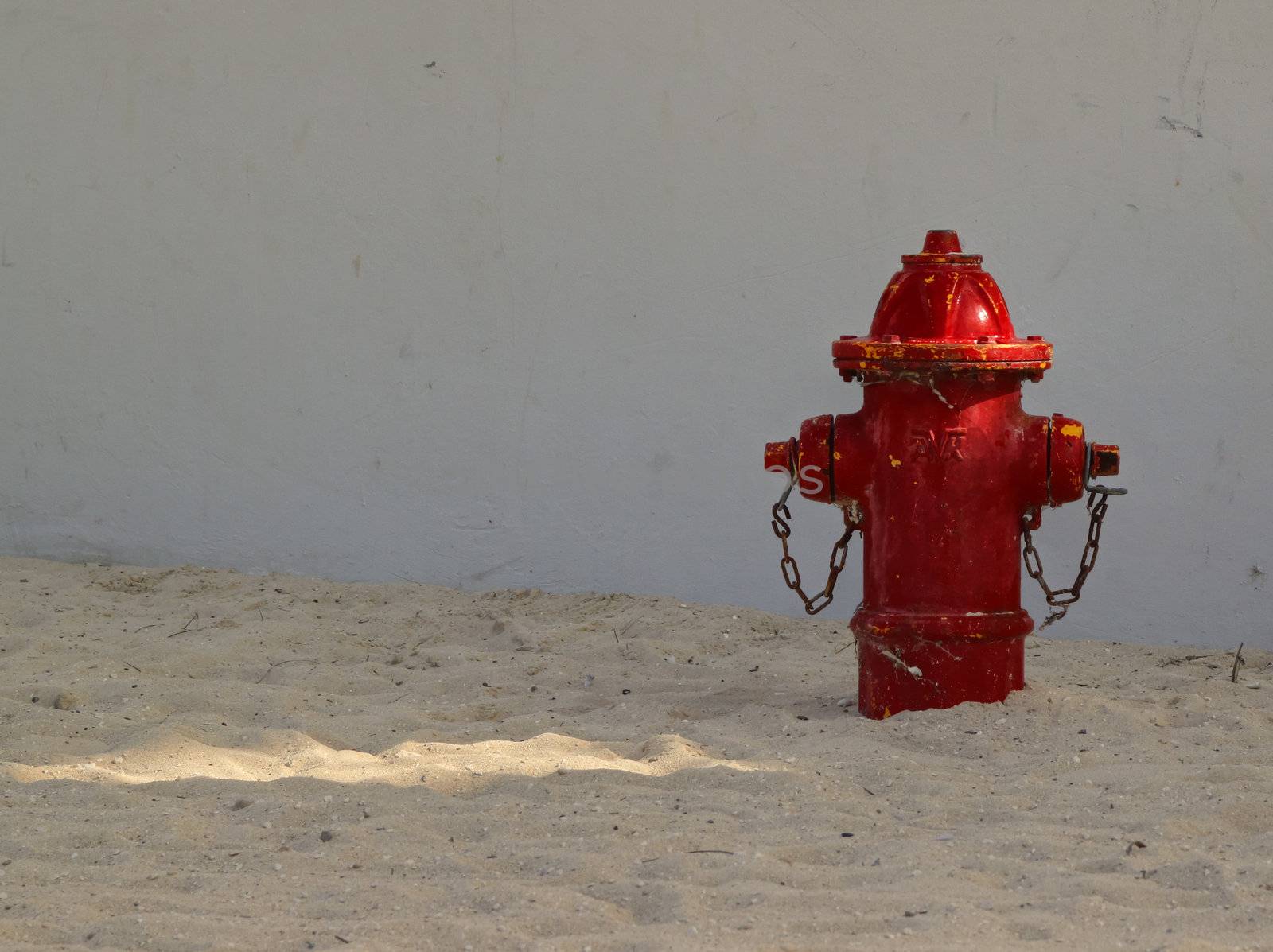 Right side view of red fire hydrant on a sandy beach