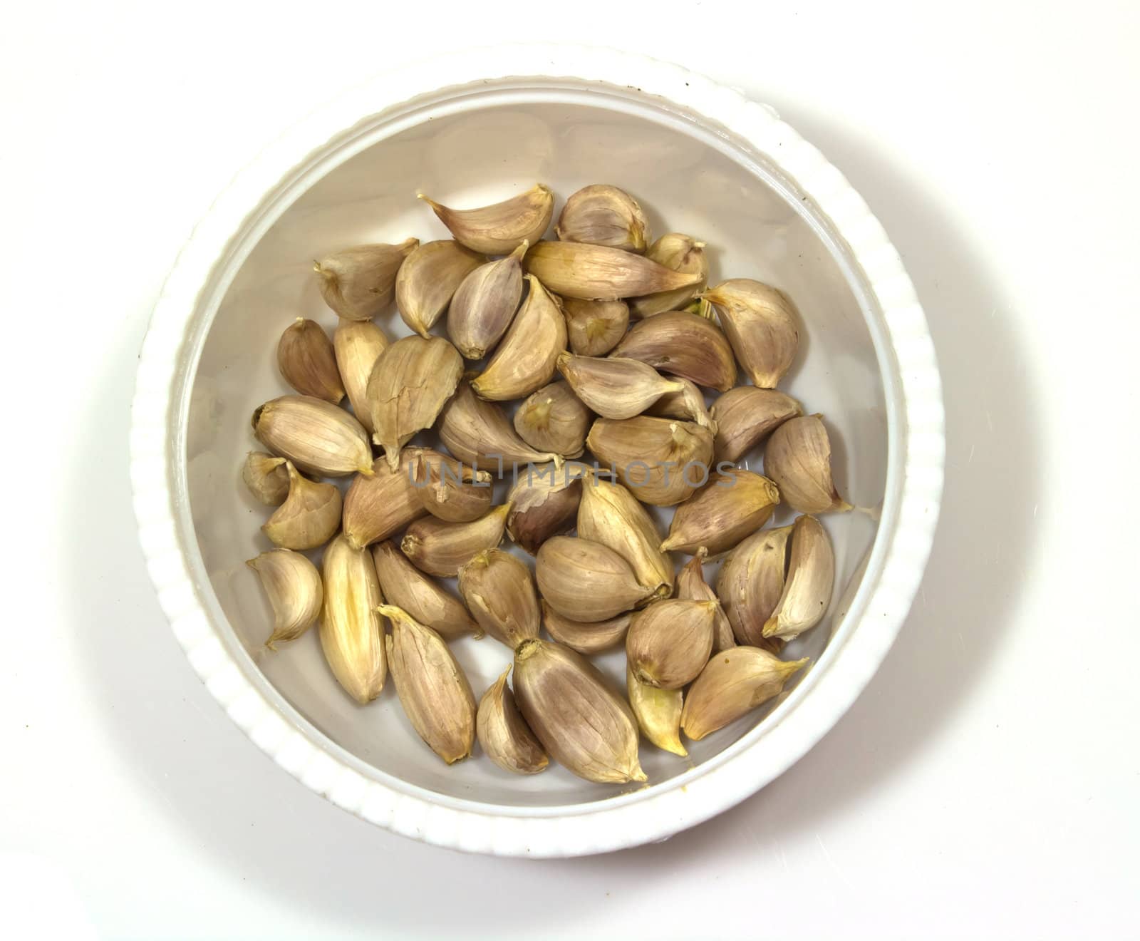 Bowl of peeled garlic on isolated background