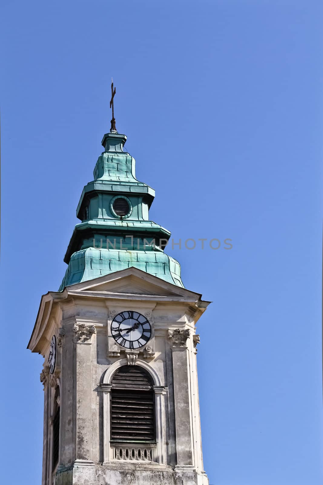 An old church tower with a clock in the center of Vienna