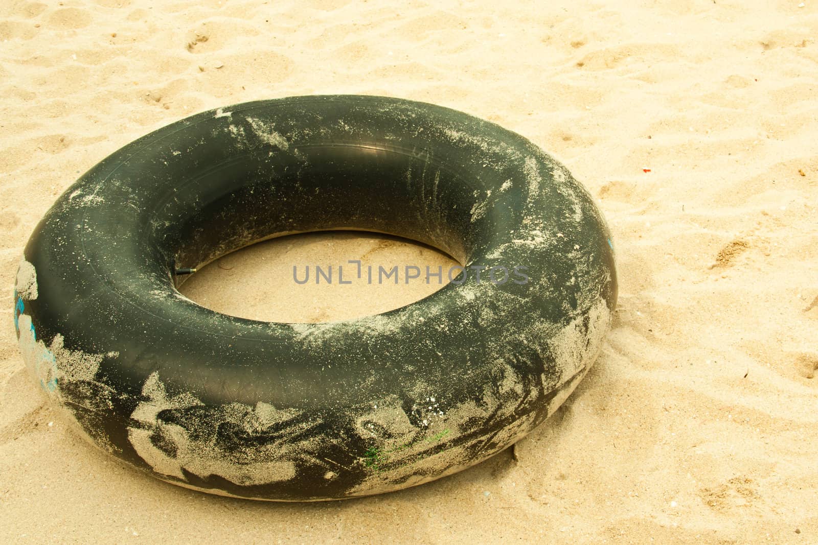 Old inner tube of car wheels on sand background.