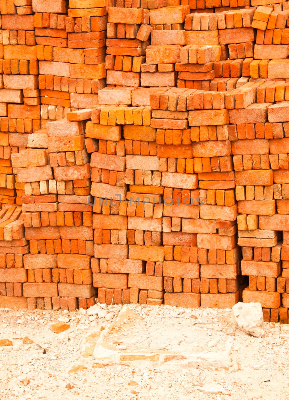 Lots of red brick. The stacked into a wall to be used in construction.
