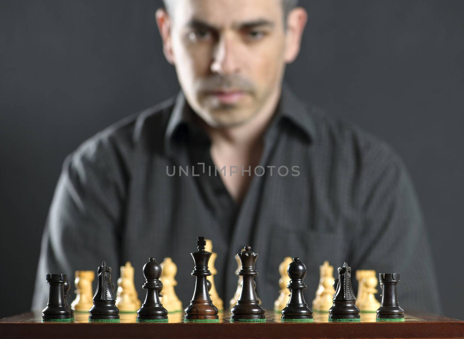 Man looking at wooden chess board thinking about first move