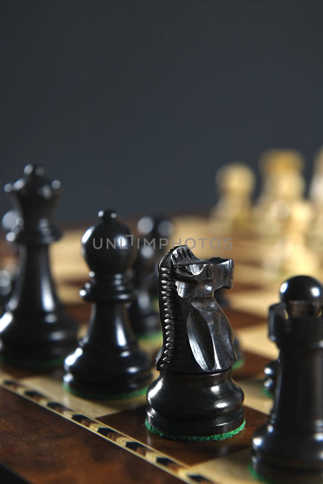 Close up of black chess pieces on wooden chessboard