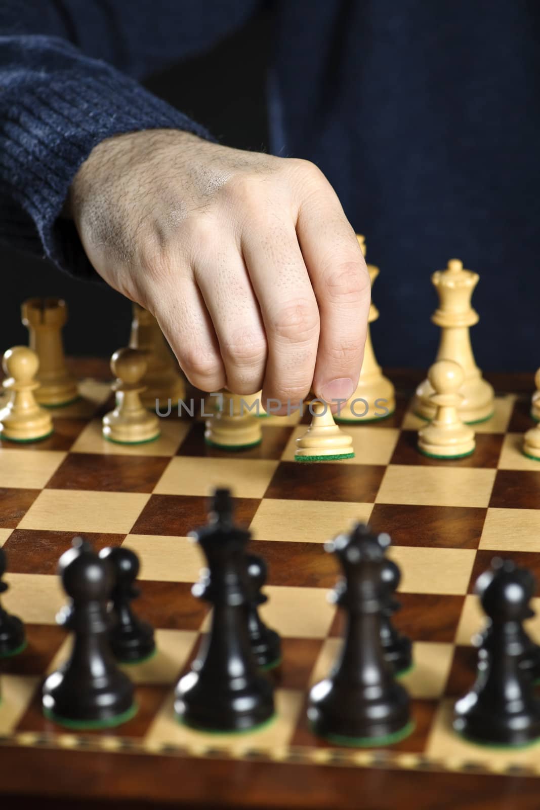 Hand moving a pawn chess piece on wooden chessboard as first move