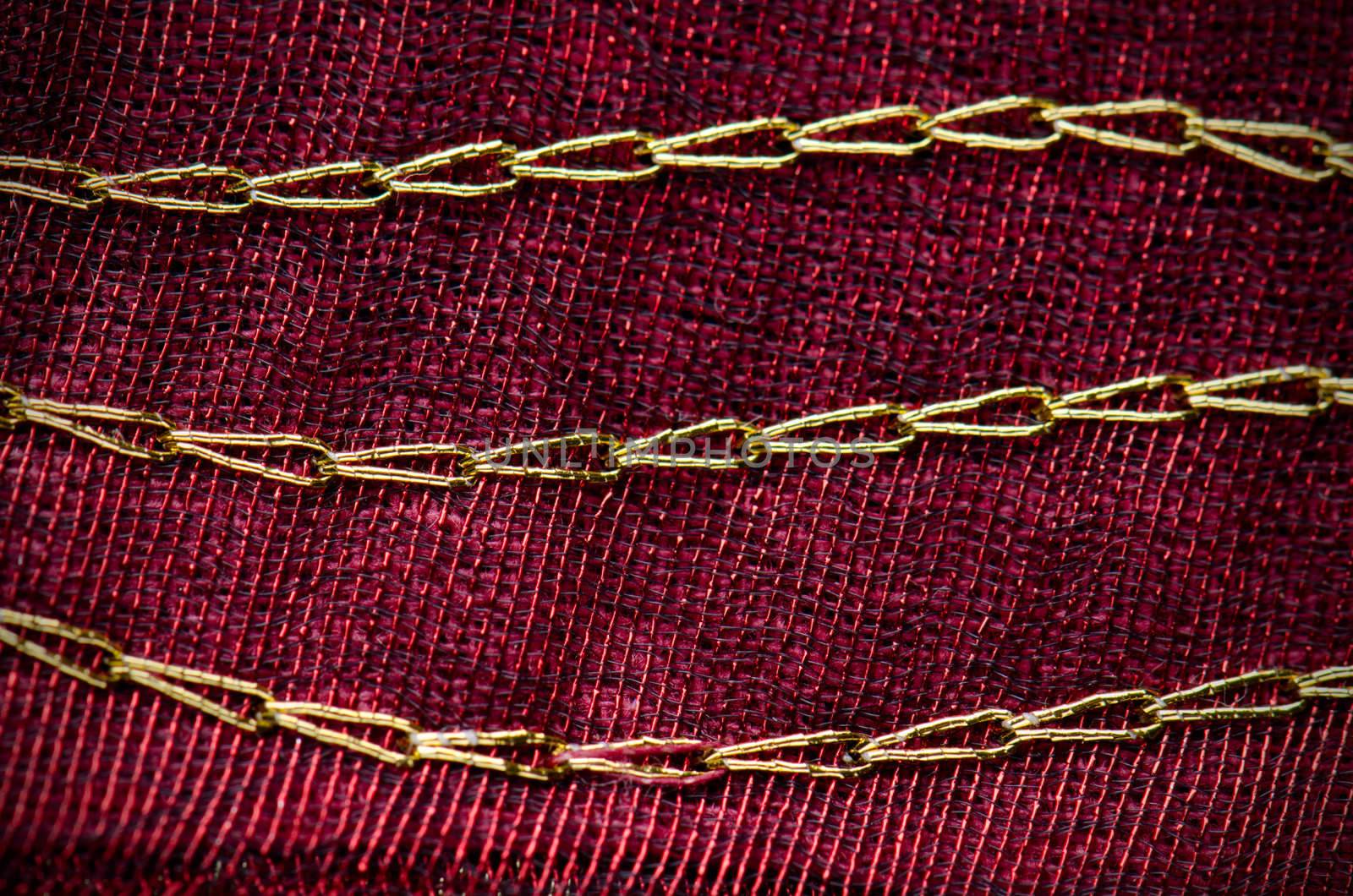 A red cloth texture with strong contrast and lines with golden decorative chains.