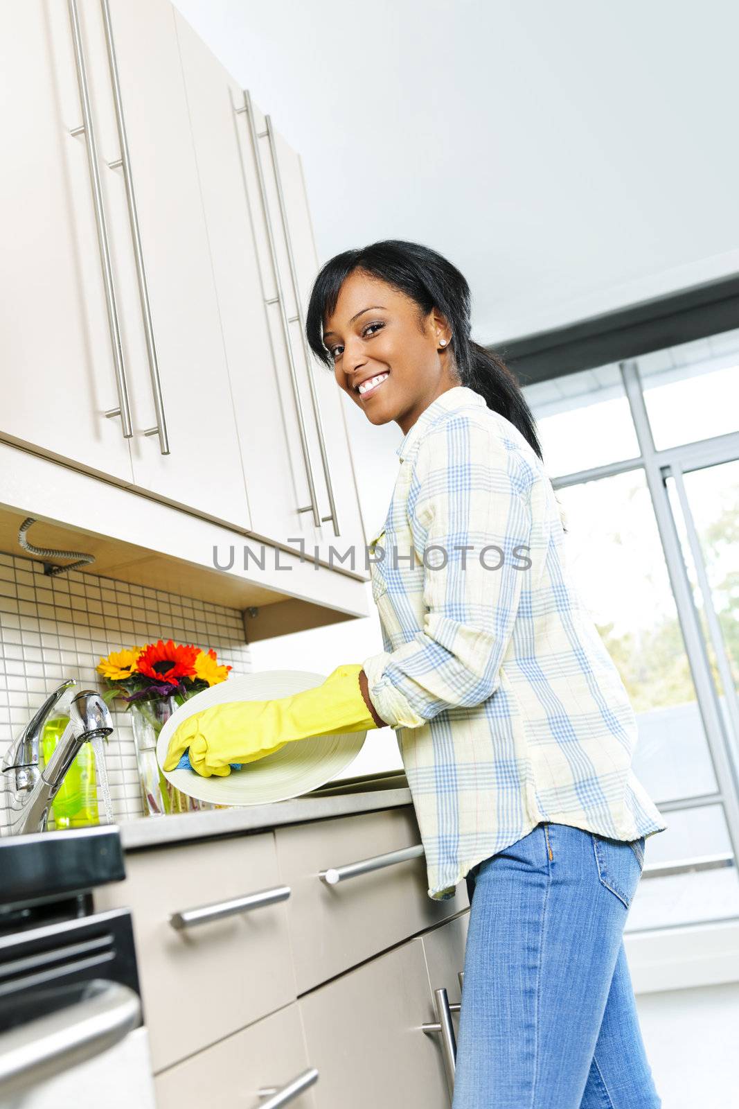 Happy young woman washing dishes by elenathewise