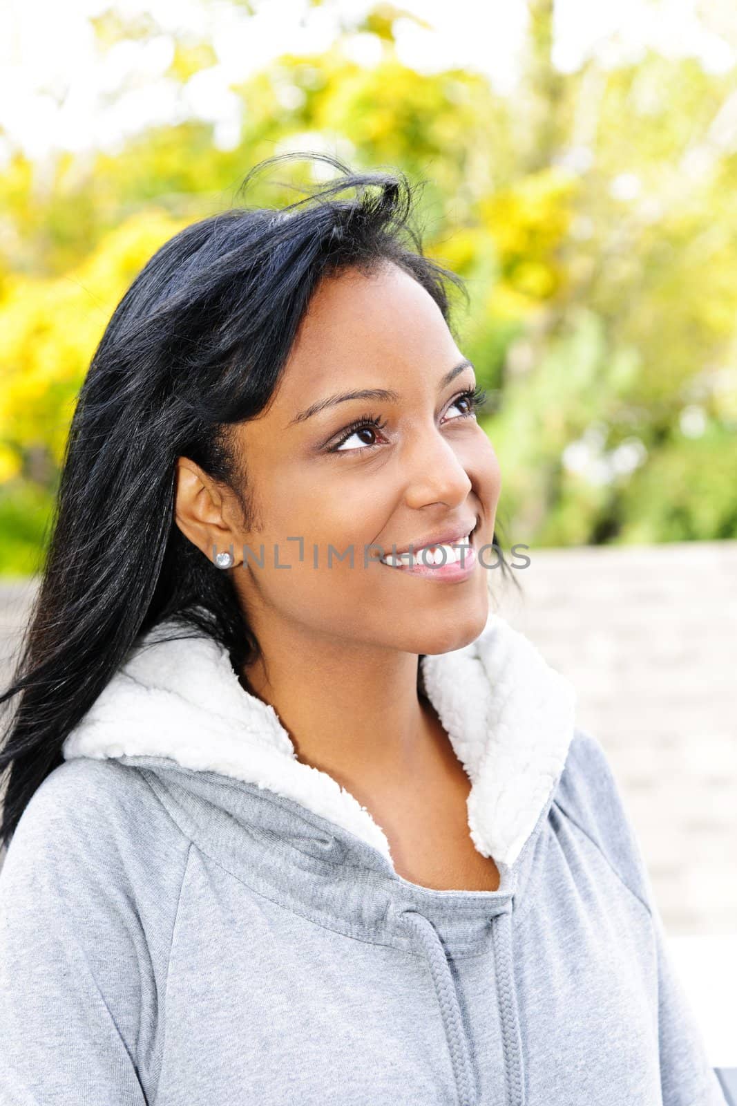 Happy young black woman looking to the side outdoors in fall