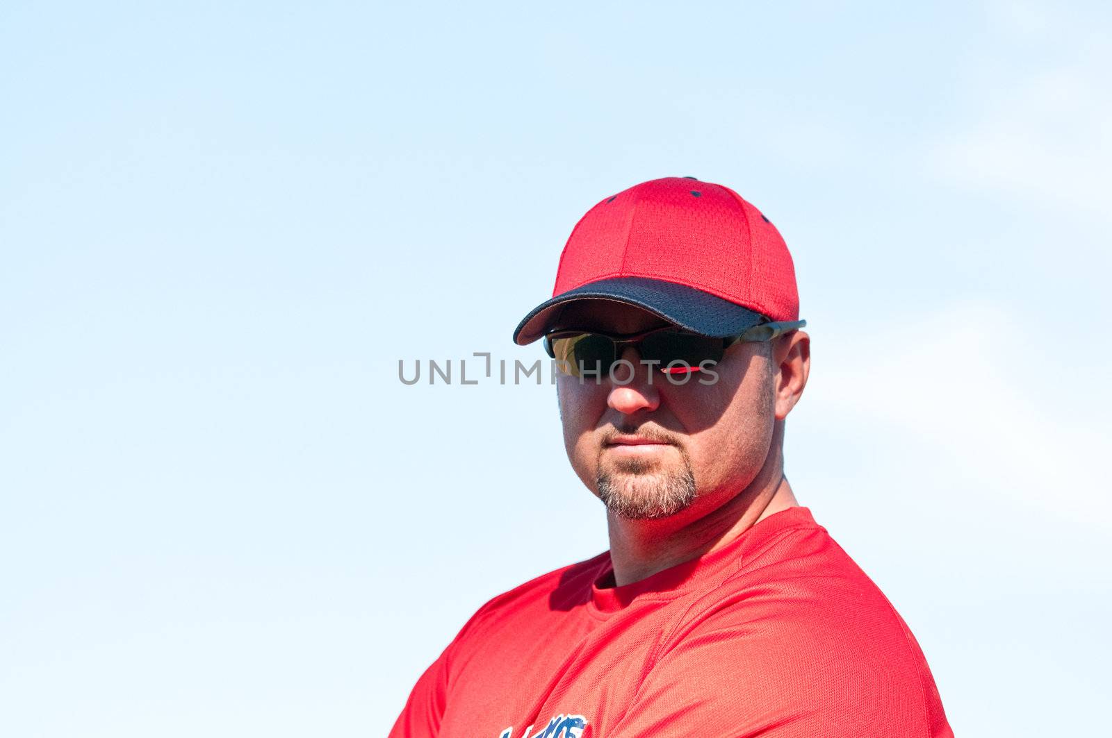 Baseball coach wearing sunglasses and looking at camera.