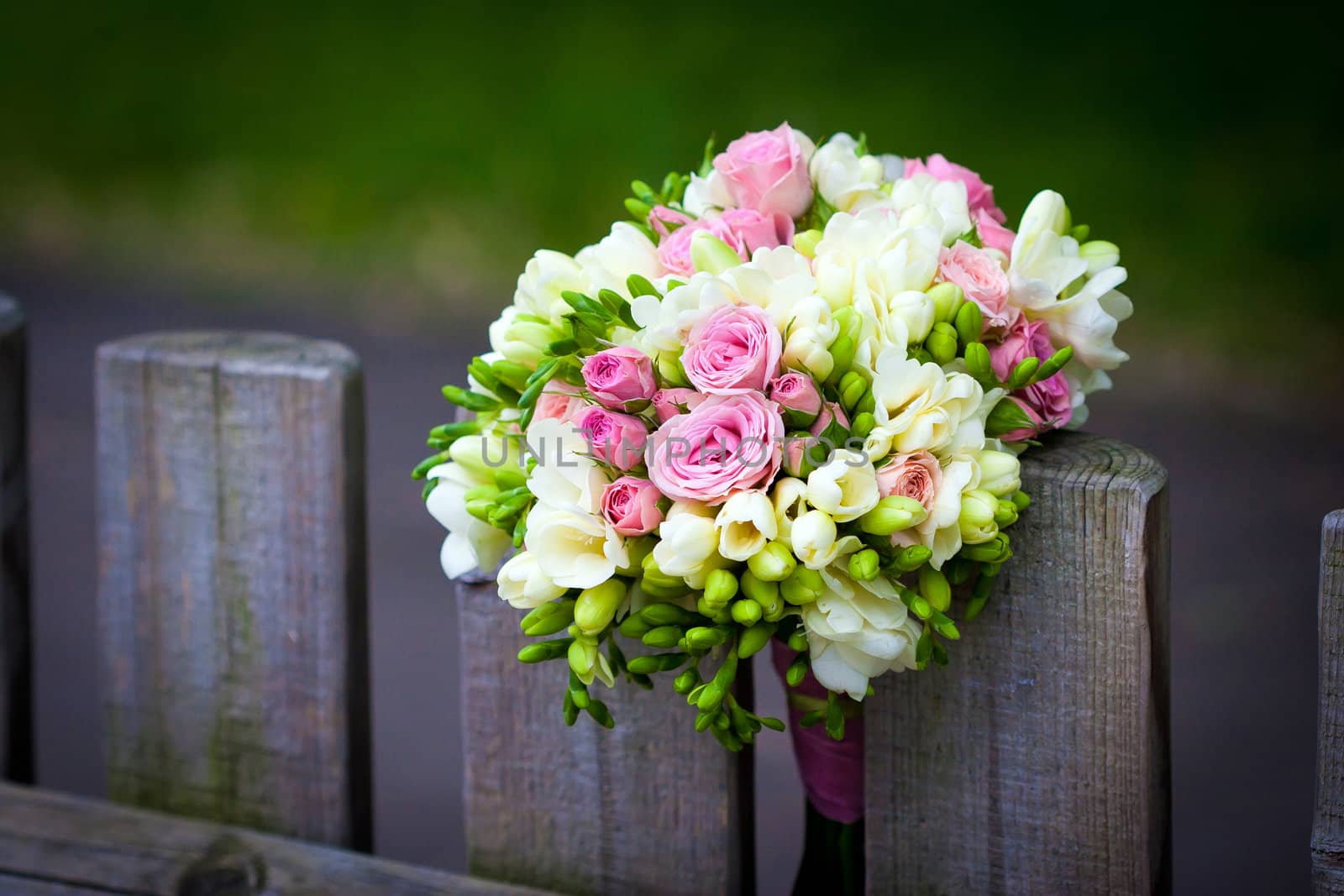 Wedding bouquet with roses and freesia on rustic country fence