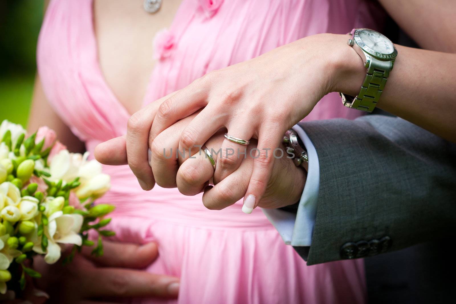 Young married couple holding hands with wedding bouquet