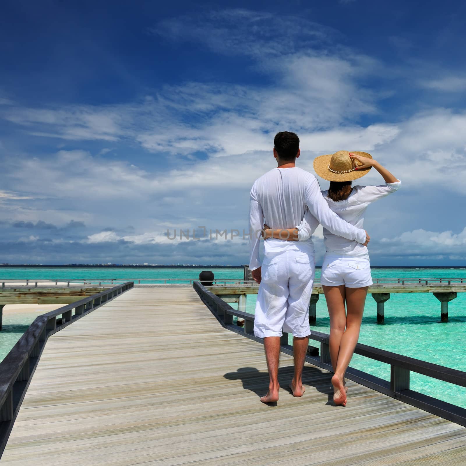 Couple on a tropical beach jetty at Maldives