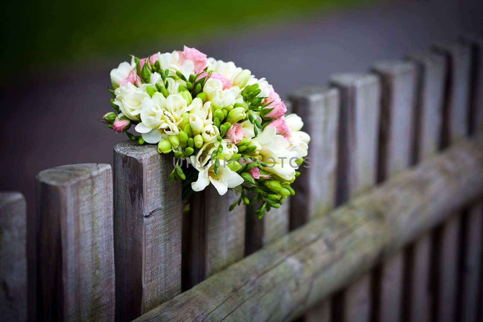 Wedding bouquet with roses and freesia on rustic country fence