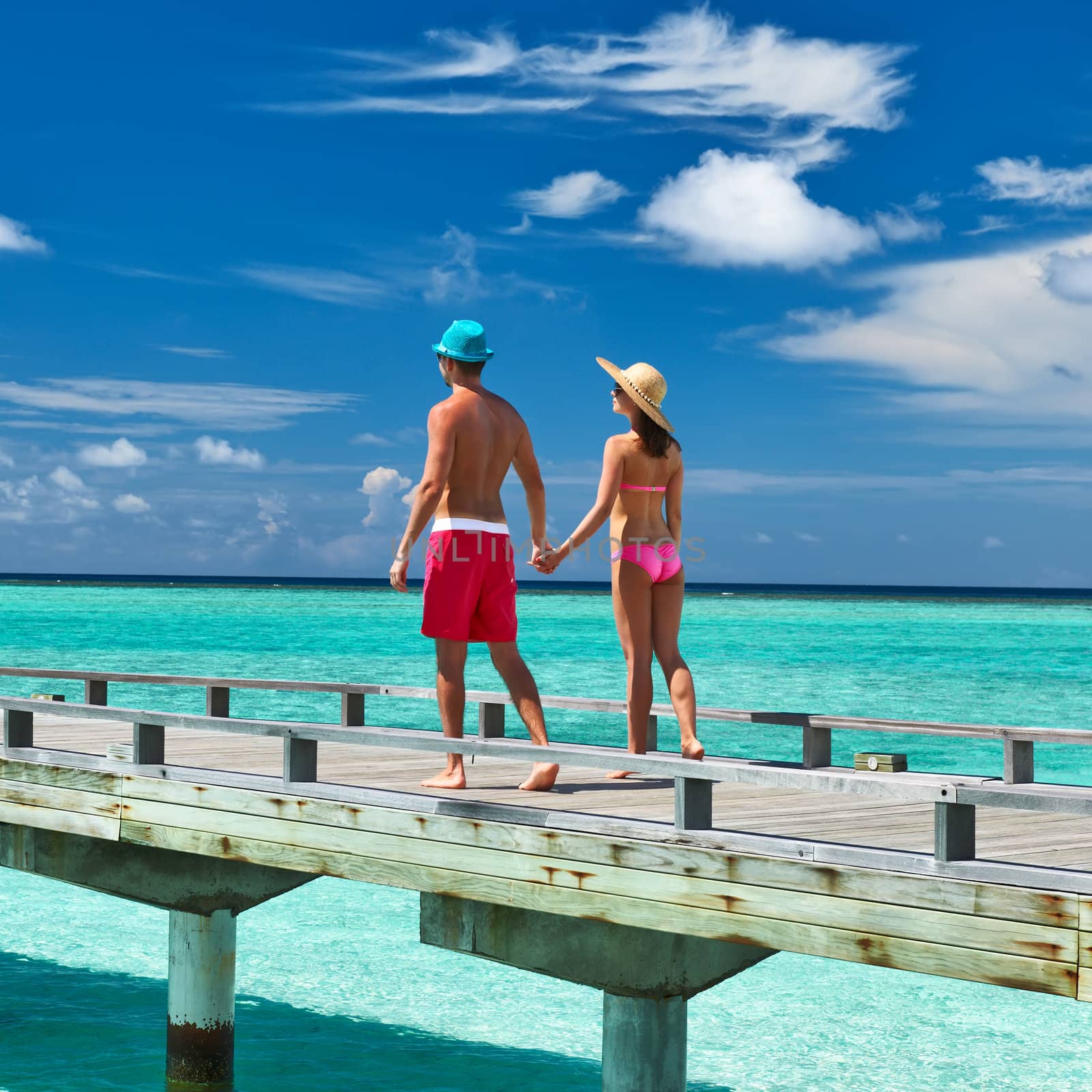 Couple on a tropical beach jetty at Maldives