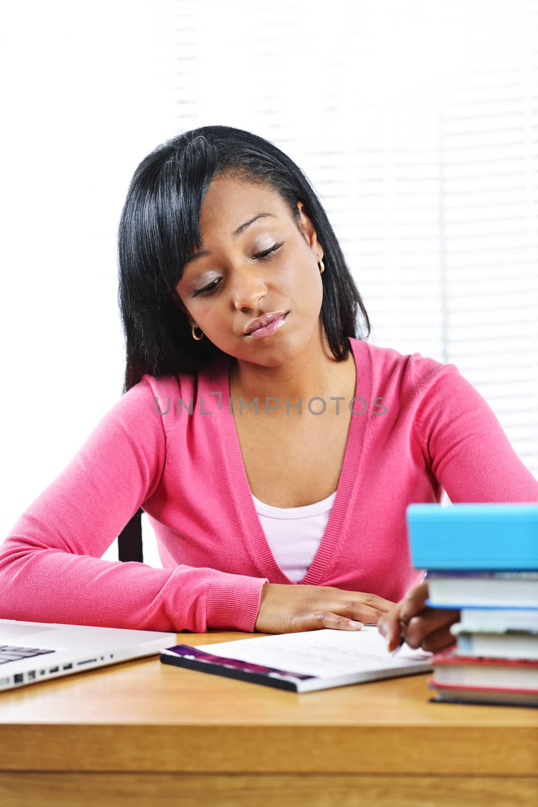 Young black female student studying at desk looking sad