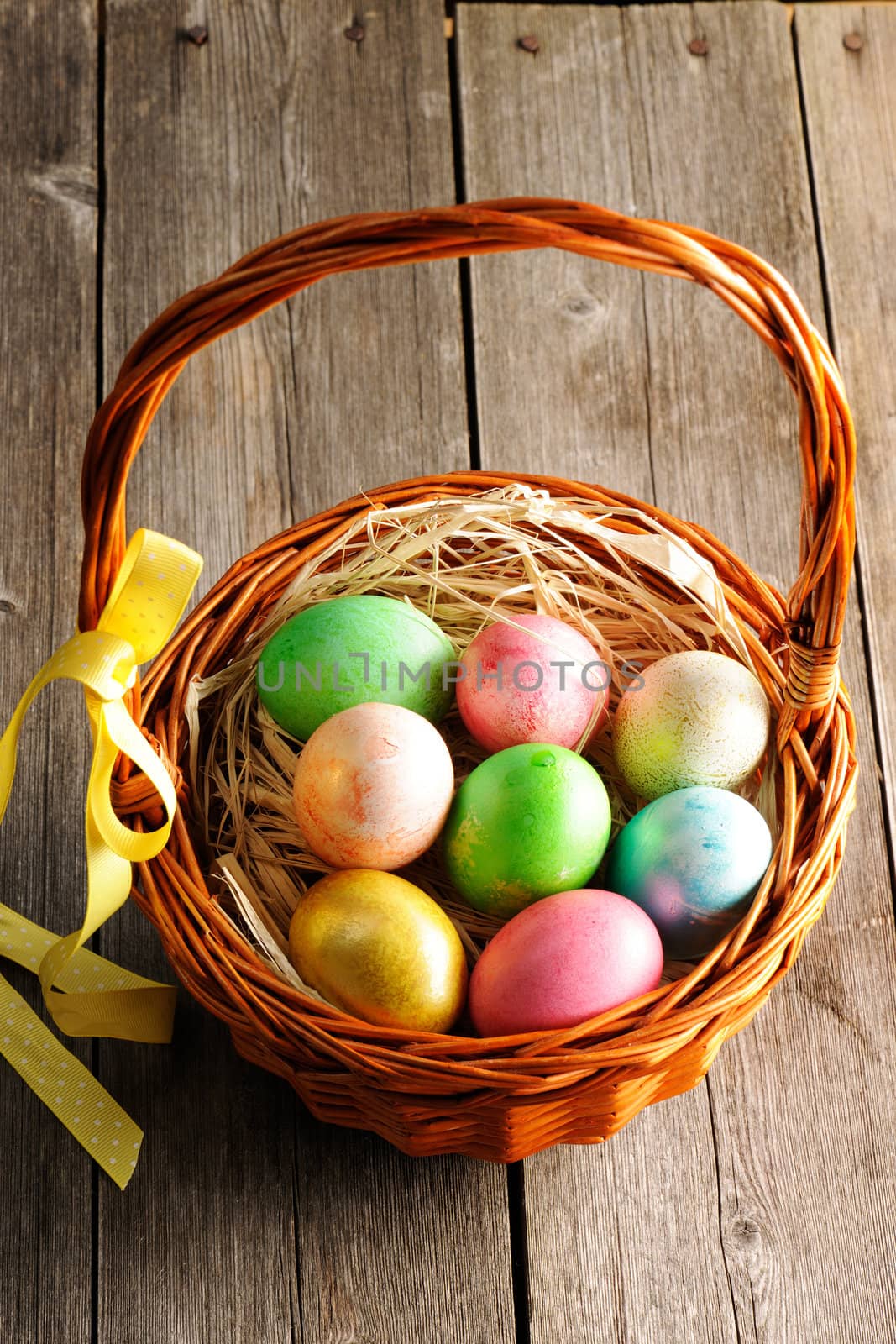 Colored easter eggs in basket on wooden table