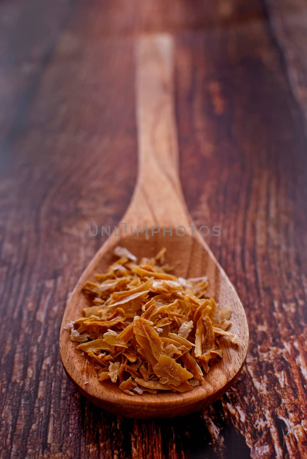 dried onion flakes in wooden spoon over wood background - selective focus