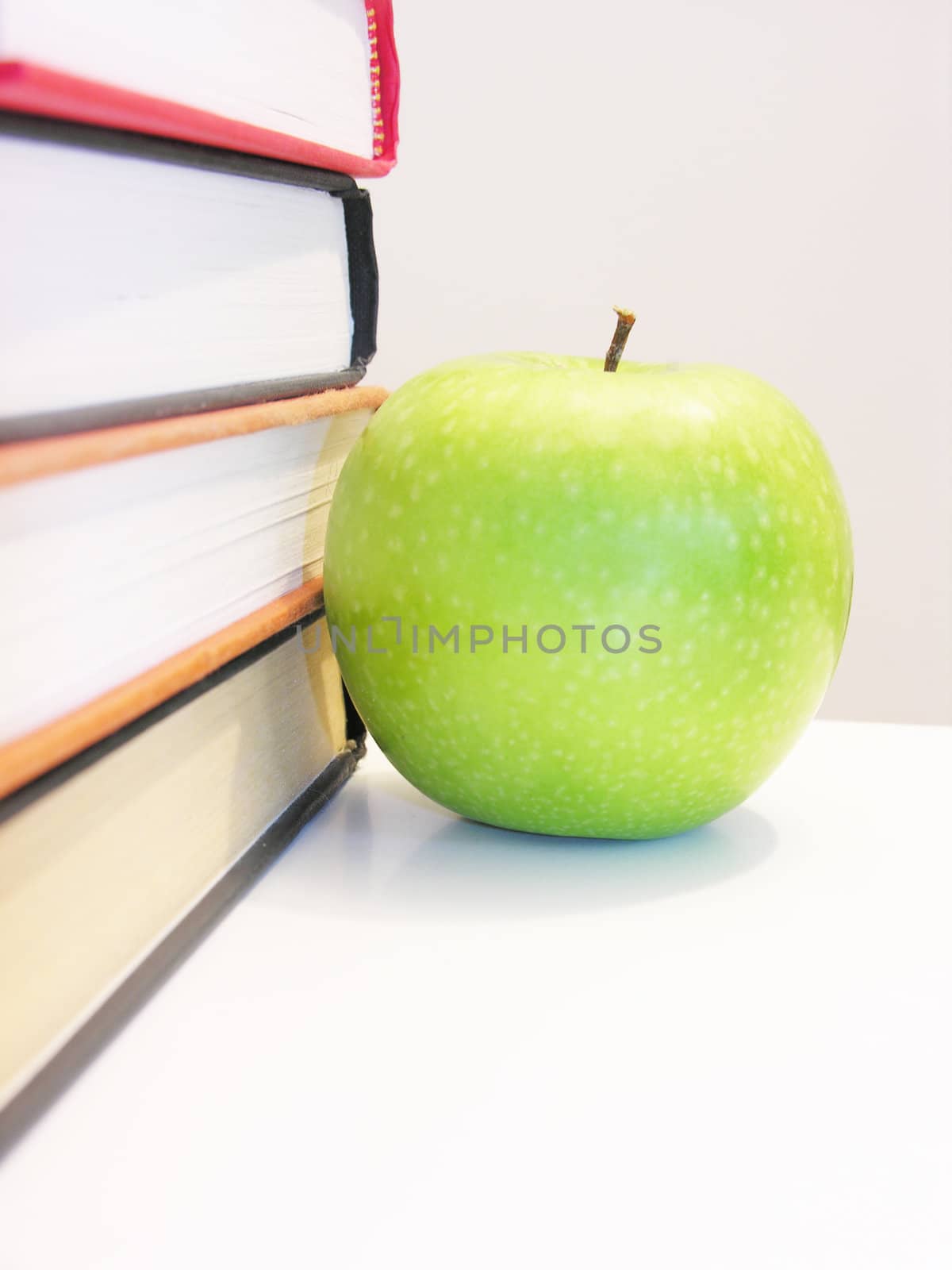 green apple with books isolated in white