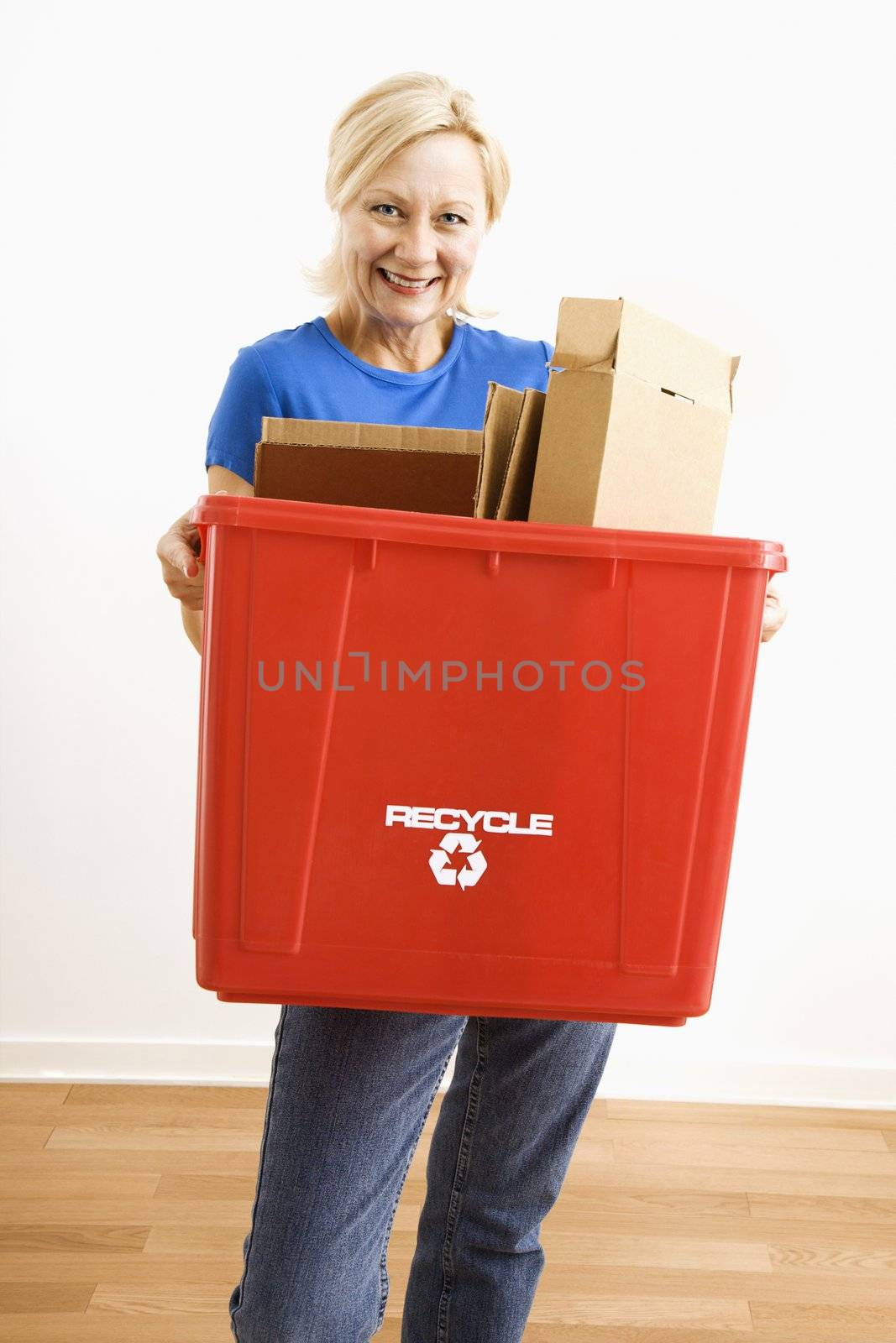 Woman holding recycling bin. by iofoto