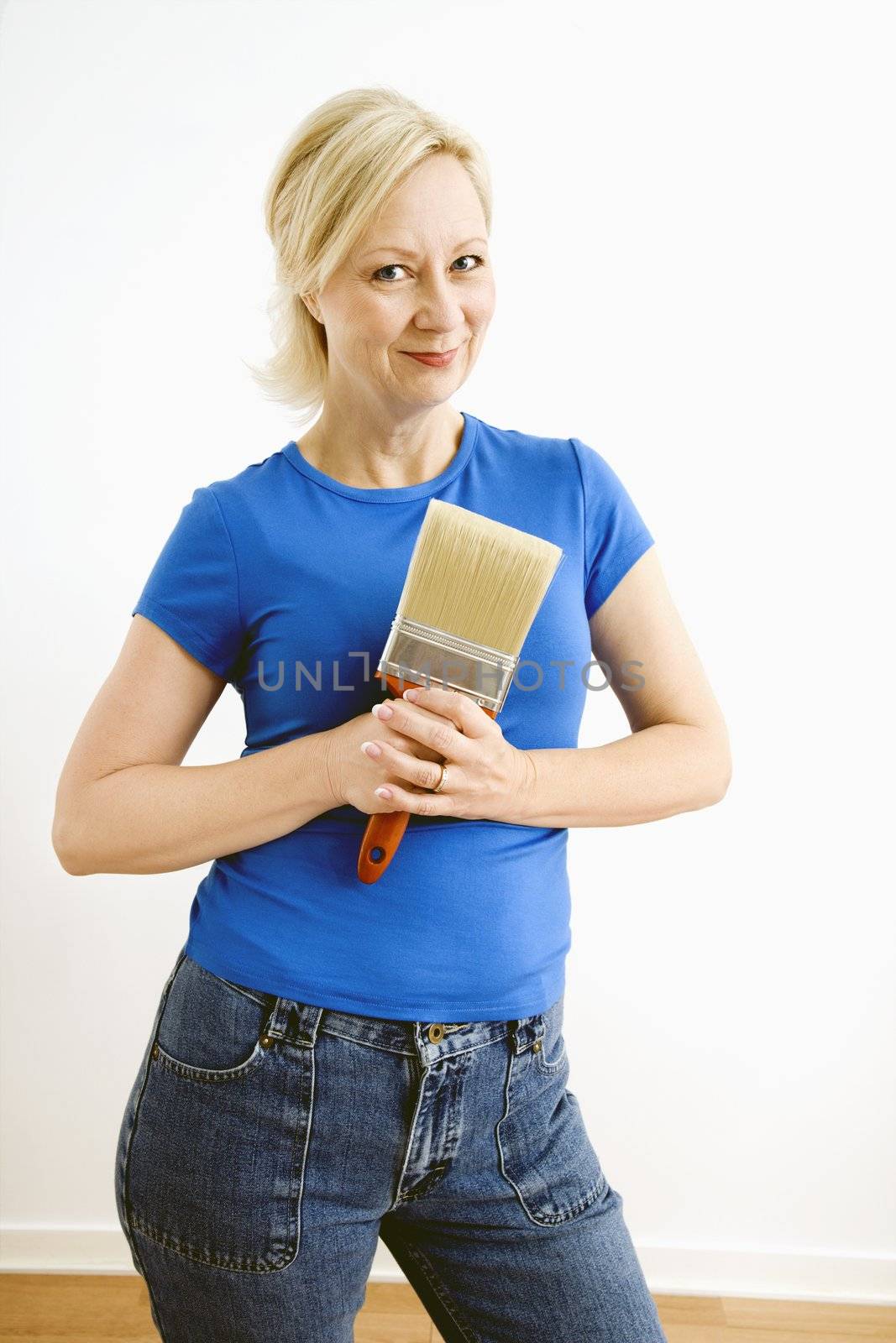 Portrait of smiling adult blonde woman holding paintbrush.