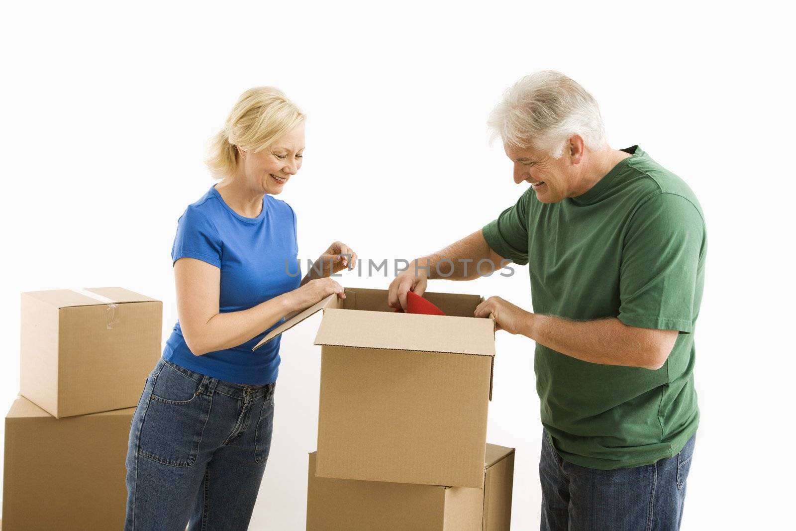 Middle-aged couple packing or unpacking moving boxes.