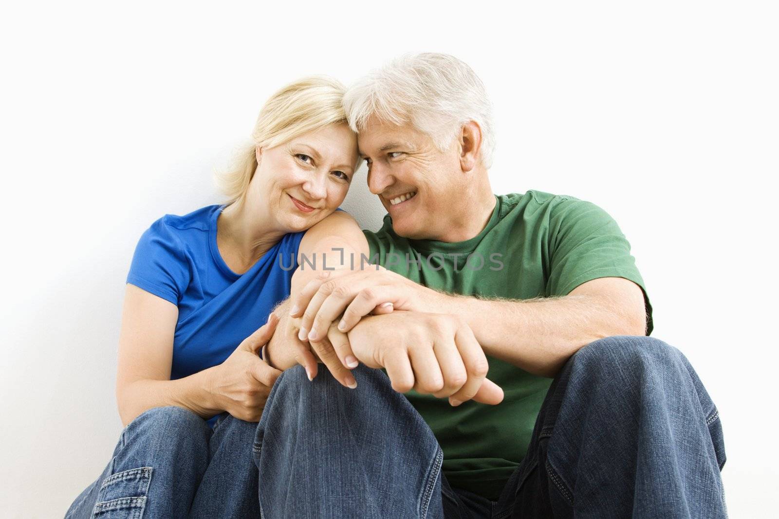 Middle-aged couple sitting together smiling.