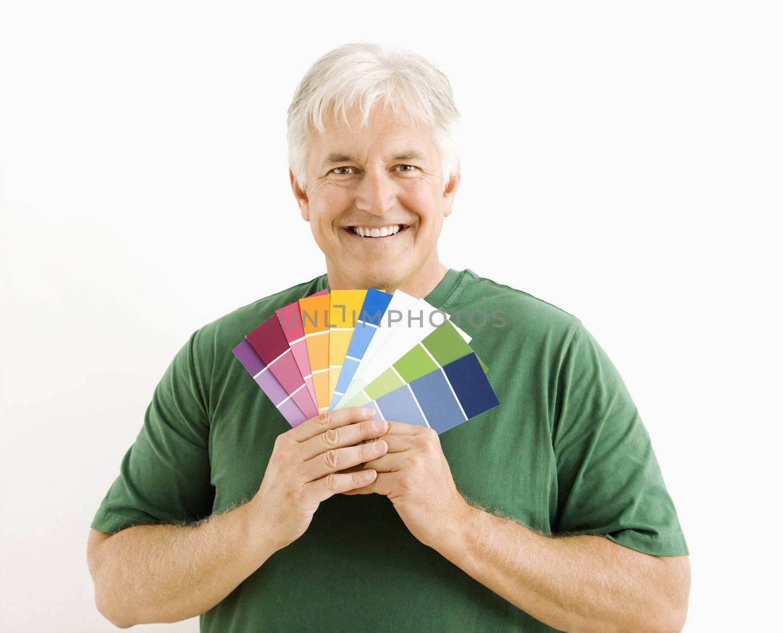 Middle-aged man holding up paint swatches.