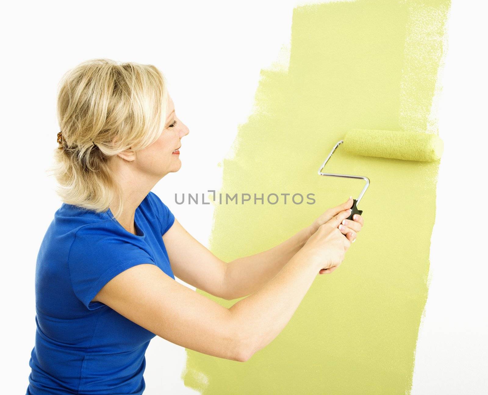 Woman painting wall. by iofoto