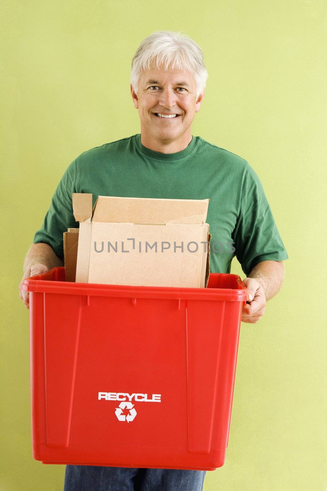 Portrait of smiling adult man holding recycling bin full of cardboard.