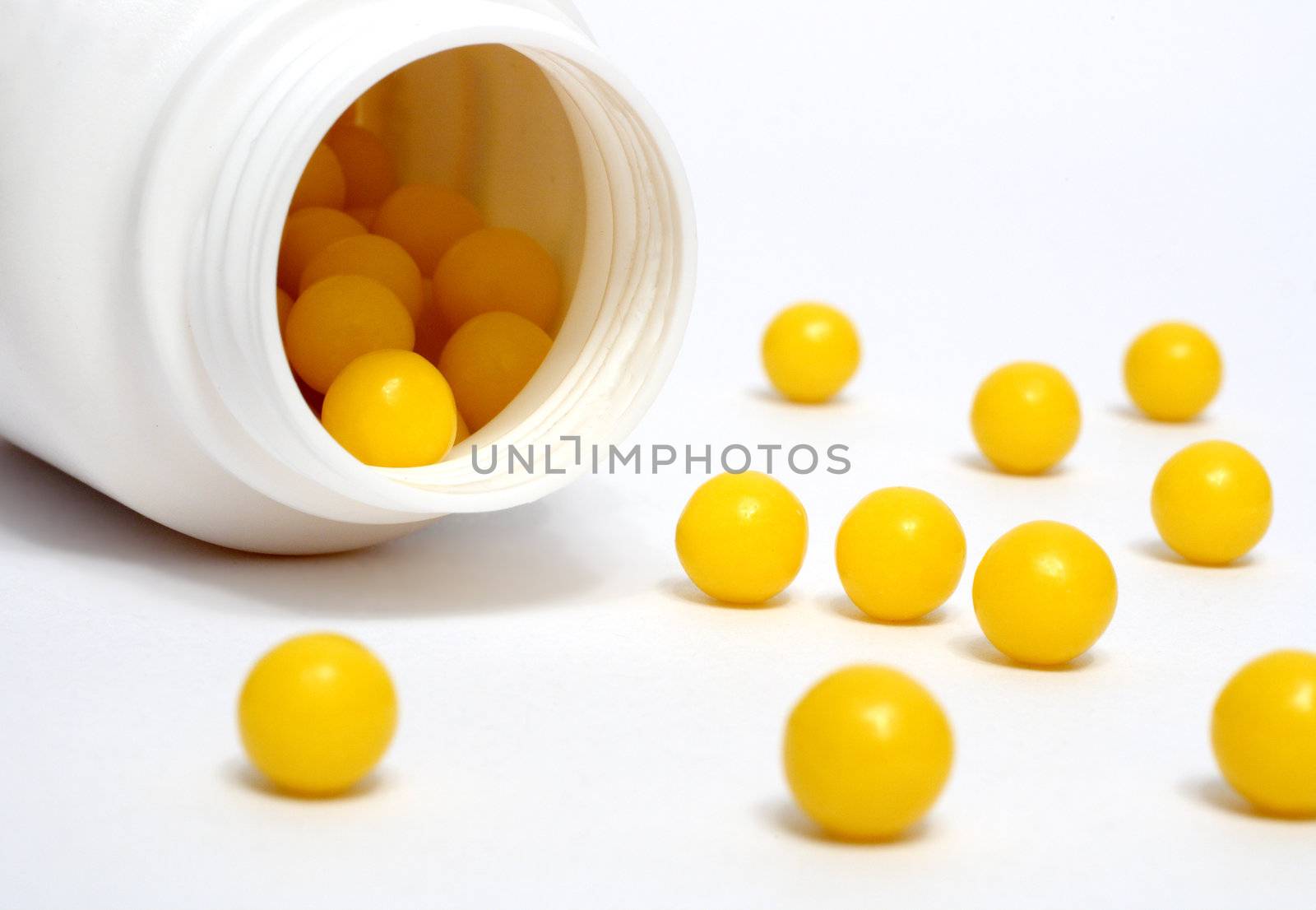 yellow vitamin dradees around white bottle