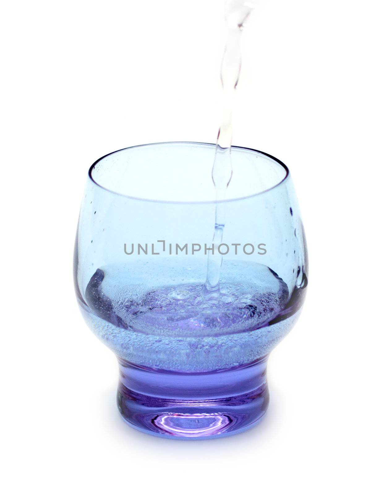 stream of water falling into purple glass isolated on white