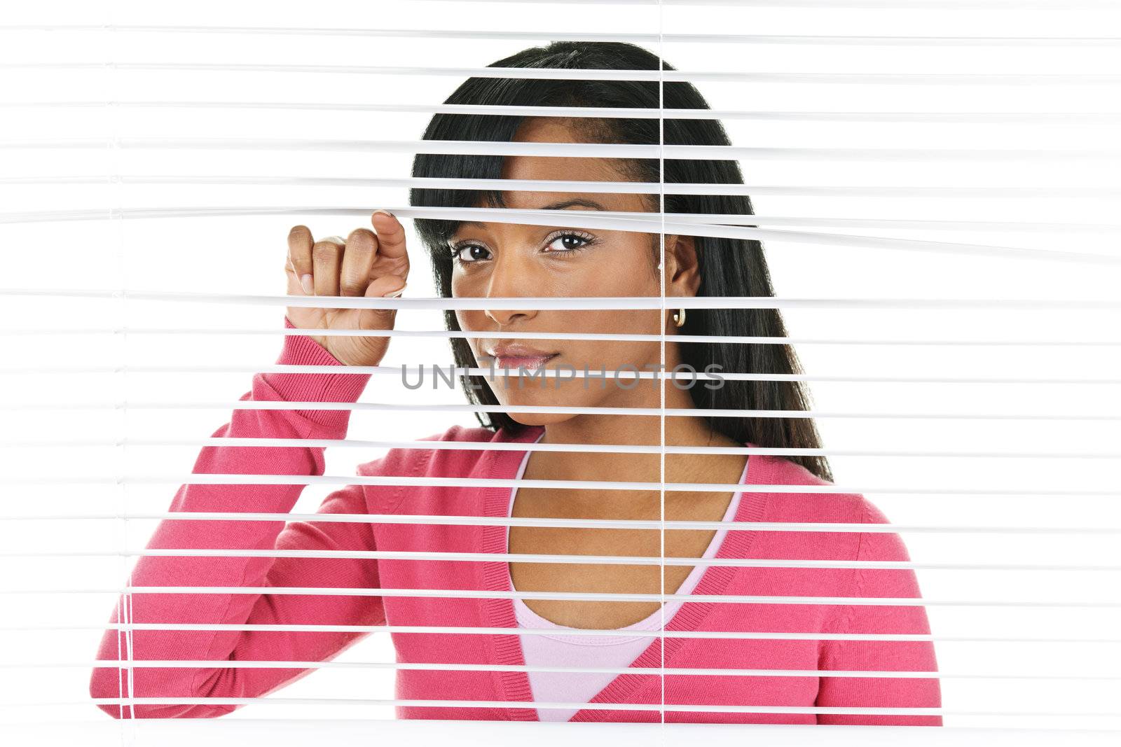 Young black woman looking through horizontal venetian blinds