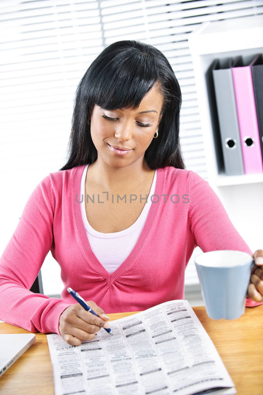 Young black female student looking in newspaper for job