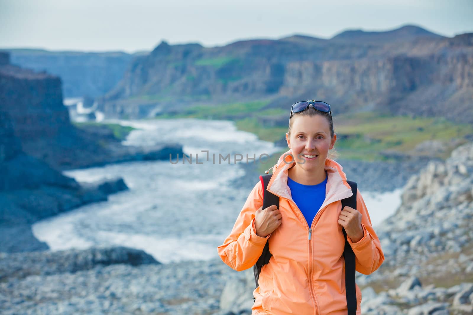 Cute woman hiking in the canyon Dettifoss waterfall in Vatnajokull National Park, Northeast Iceland.
