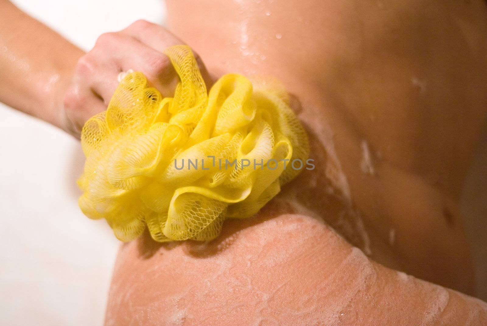 Woman with a yellow bathroom sponge taking a shower.