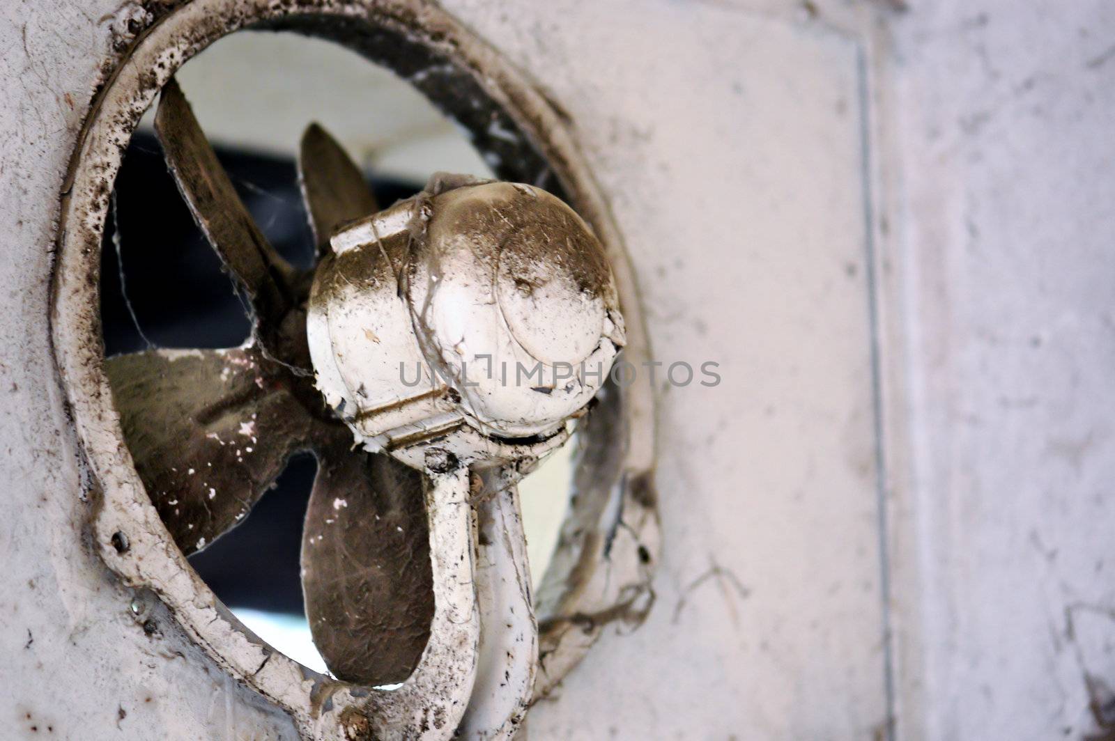 Dusty weathered ventilation fan at an abandoned house.