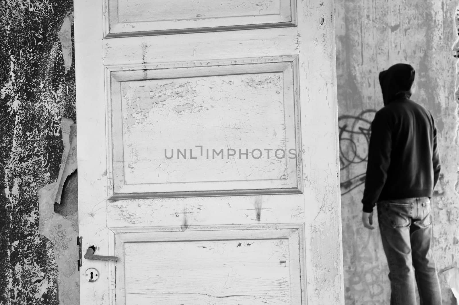 Hooded figure in abandoned house. Black and white.