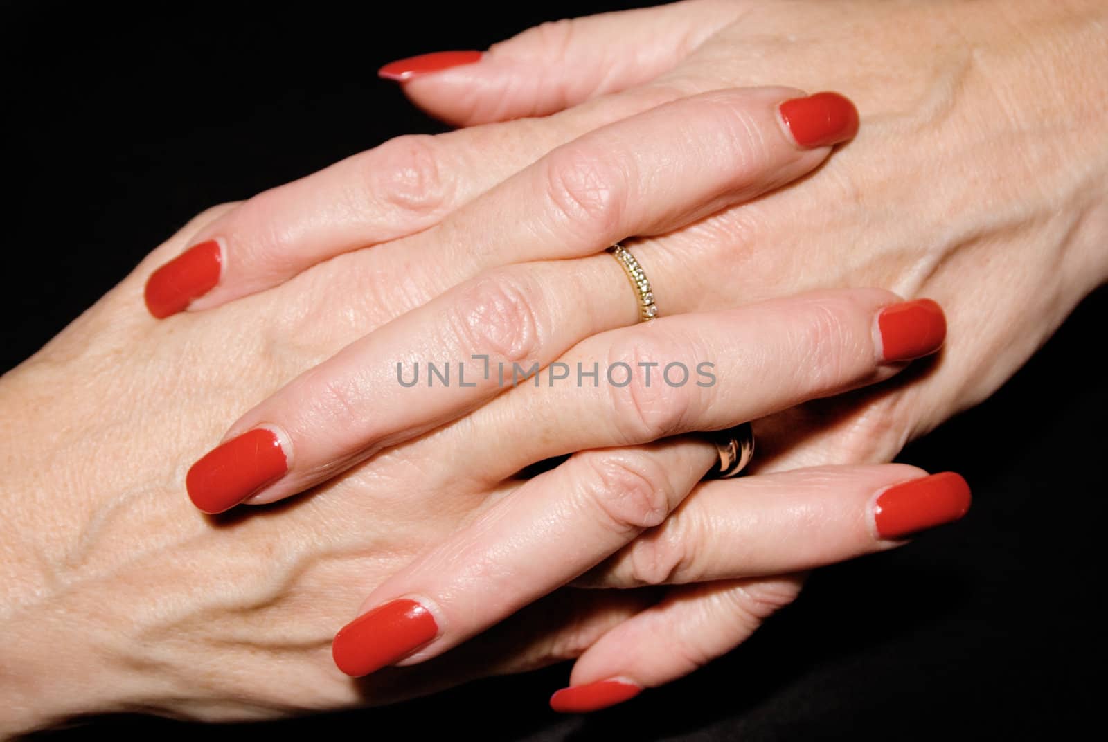 Mature woman with painted fingernails praying. Isolated on a black background.