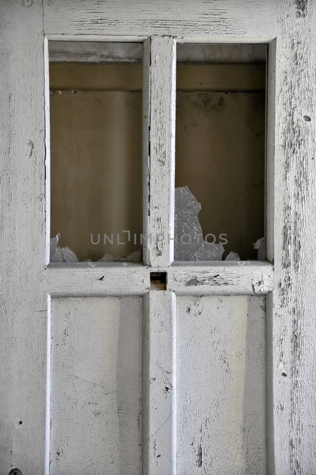 Weathered flaking paint wooden door and broken glass.