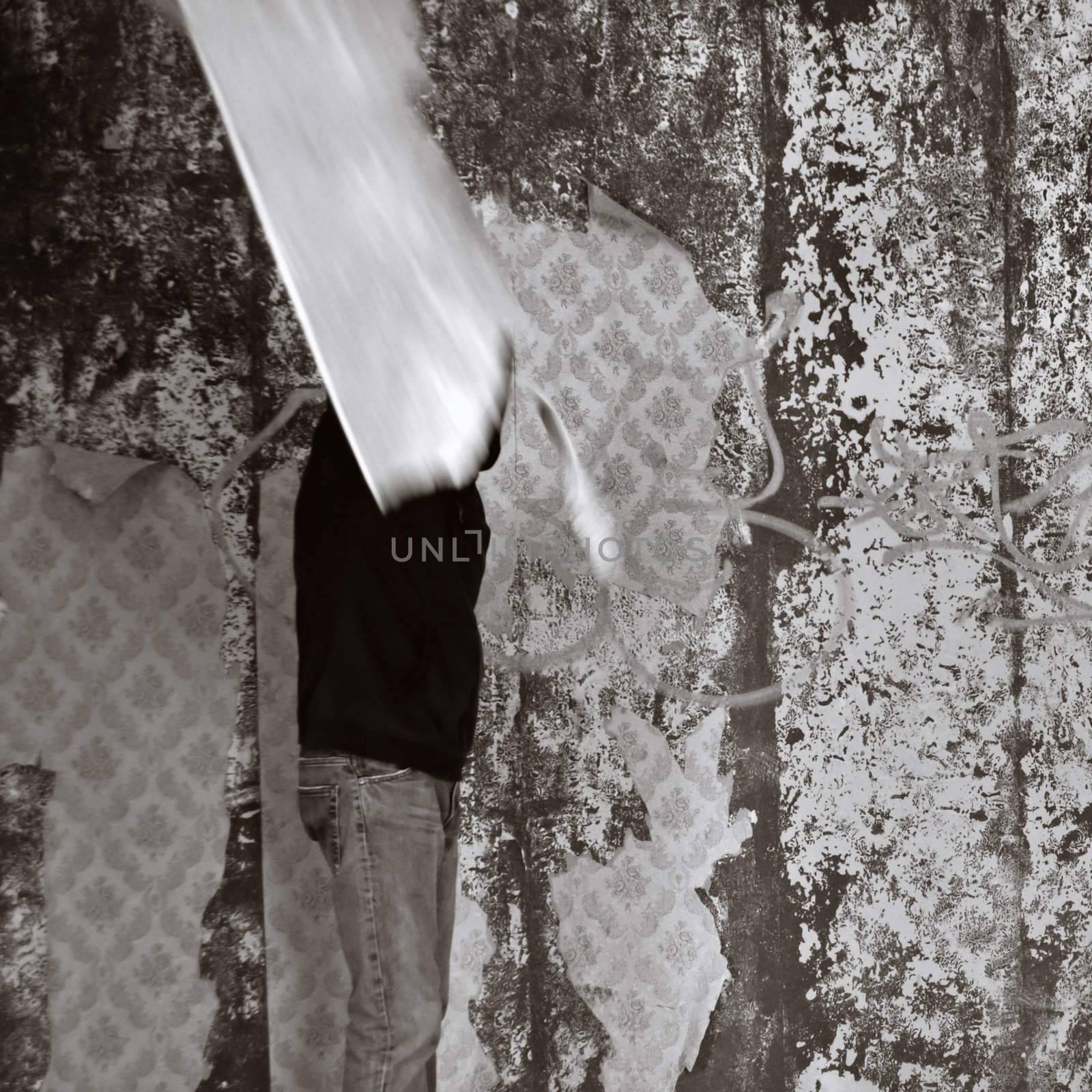 Obscured figure in empty room with torn wallpaper. Motion blur, black and white.
