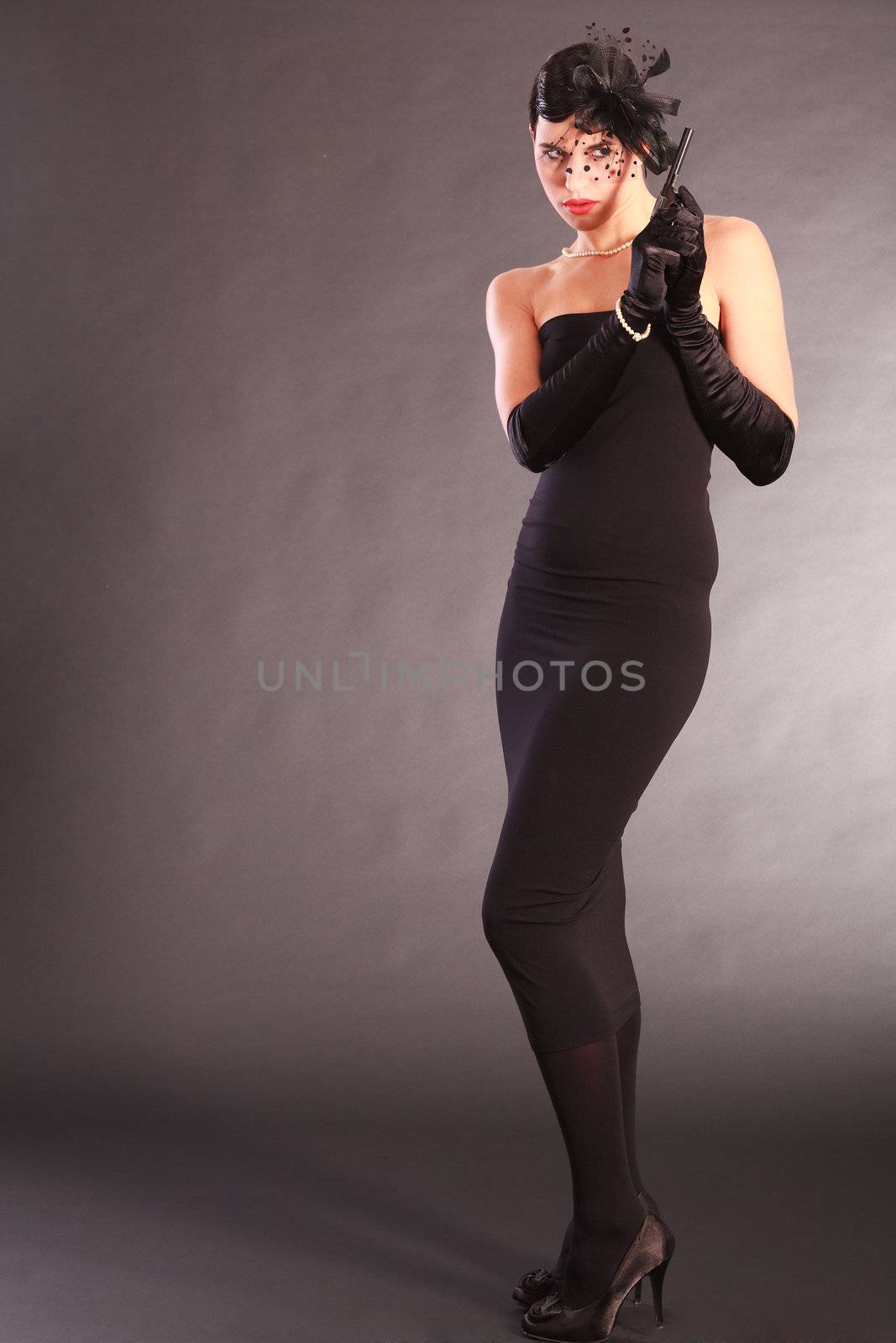 Elegant woman in black catsuit with gun and hair bow