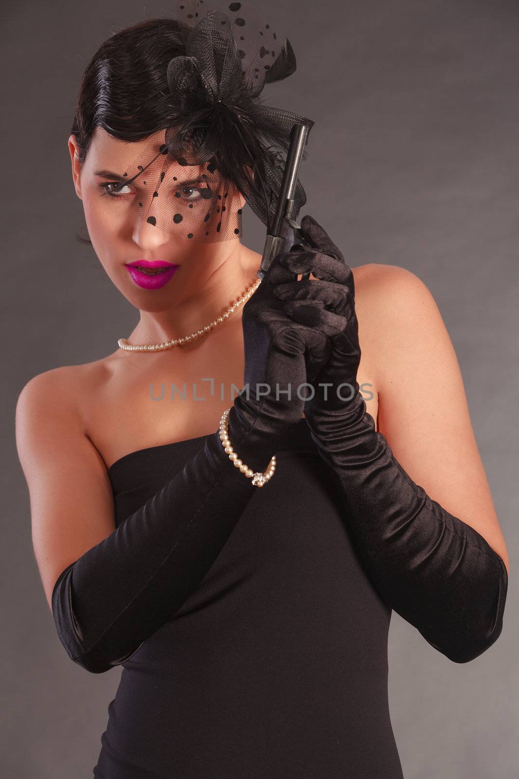 Elegant woman in black dress with gun and bow in her hair