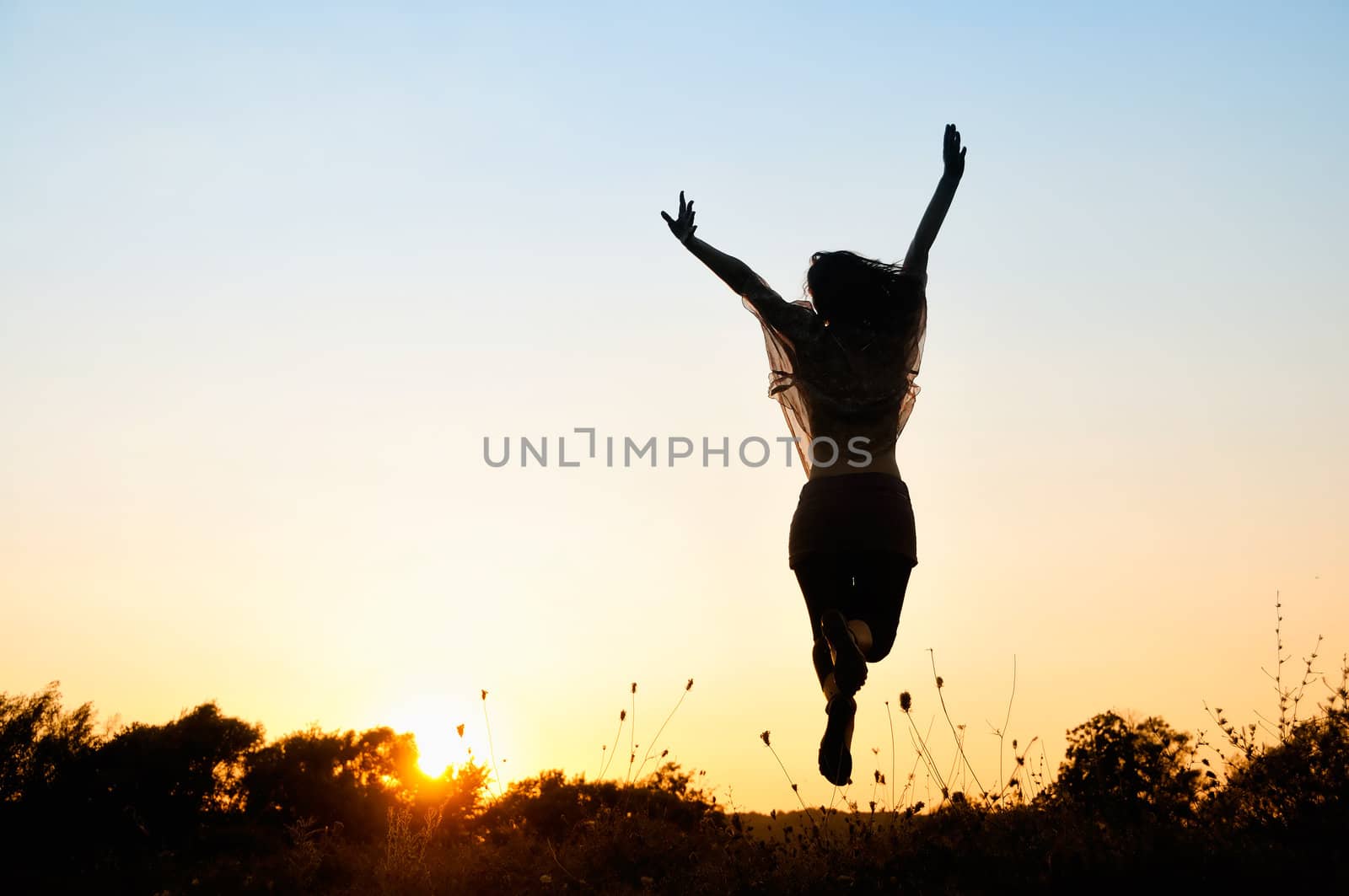 Silhouette of unrecognizable person jumping over sunset