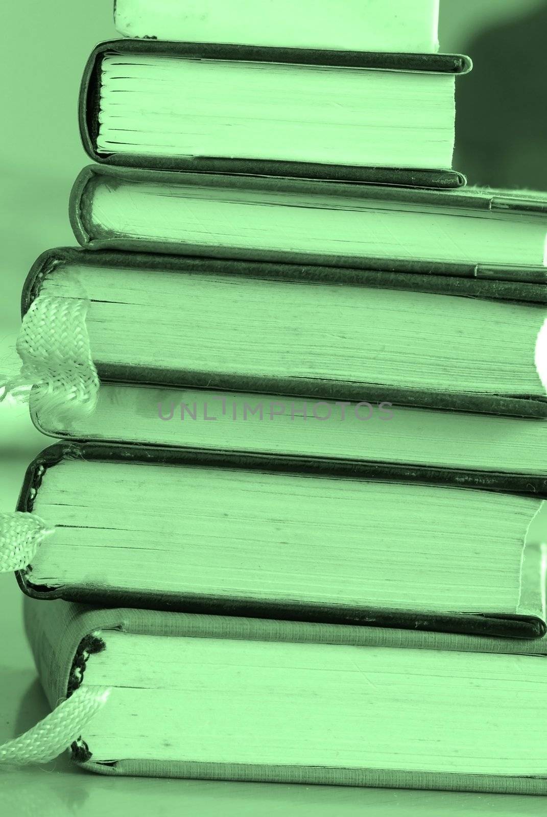 old dusty opened books stack on table, green toned