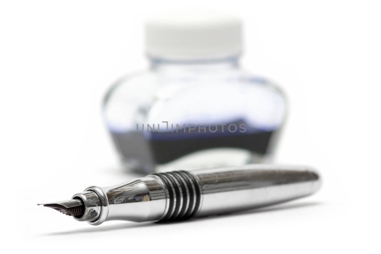 Silver fountain pen in front of an ink pot. Isolated on a white background. Shallow depth of field.