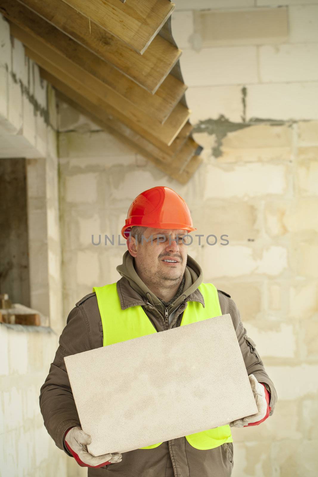 Builder with concrete block near new building by A.L.